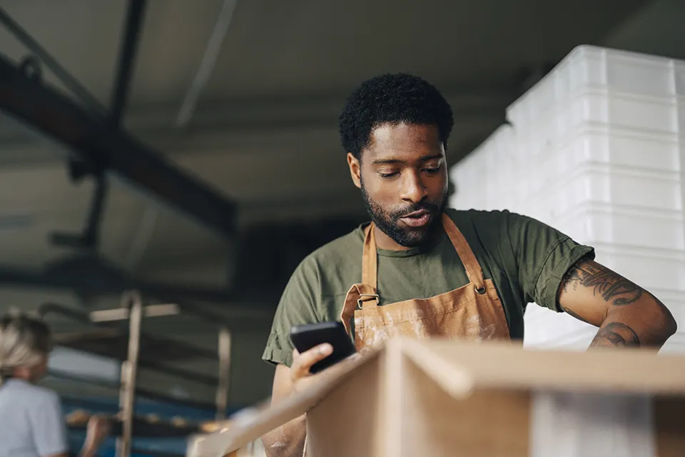 Small business owner using a mobile phone while managing orders